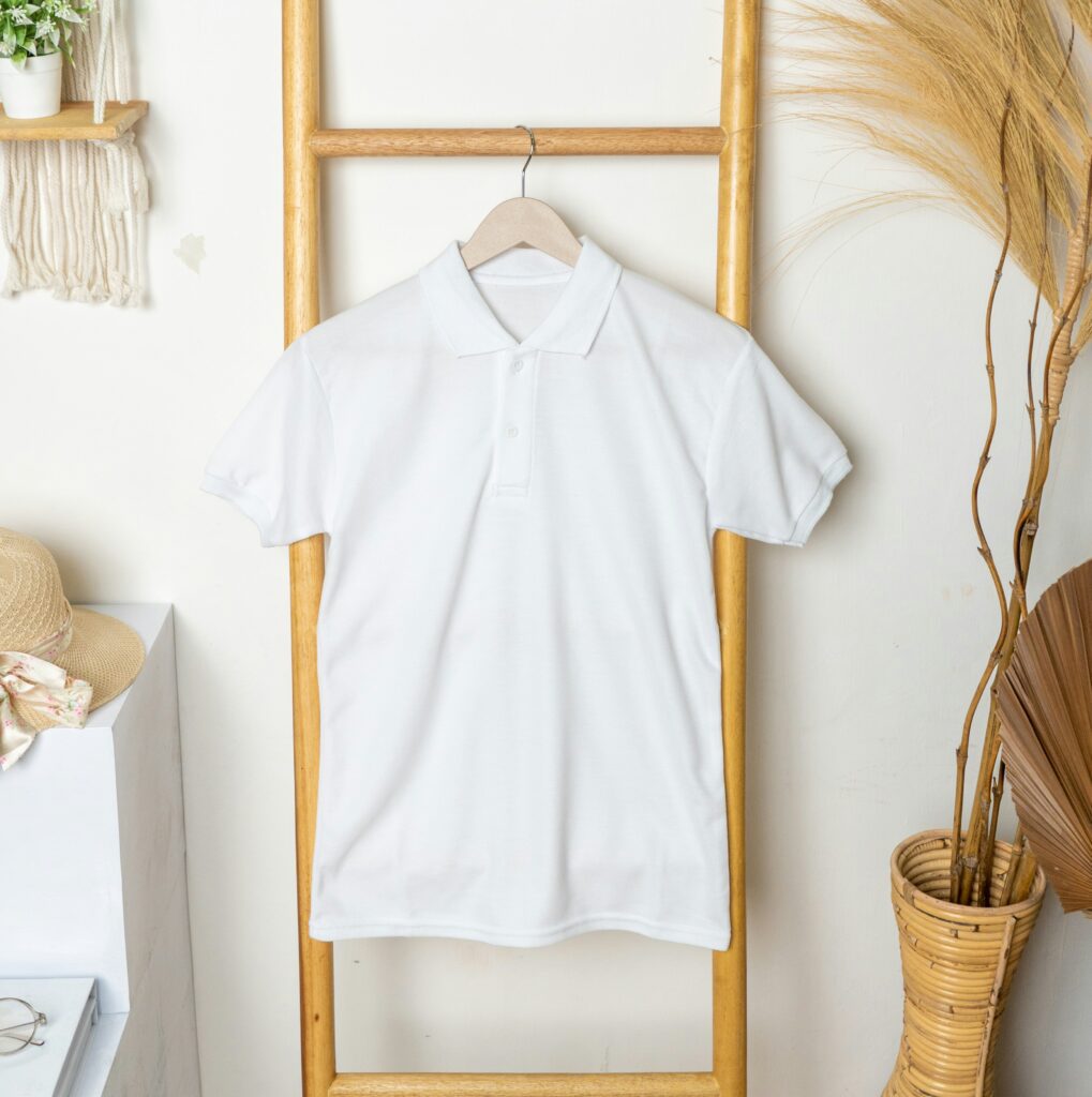 White polo t-shirt hanging on a wooden ladder in a minimal boho-style room