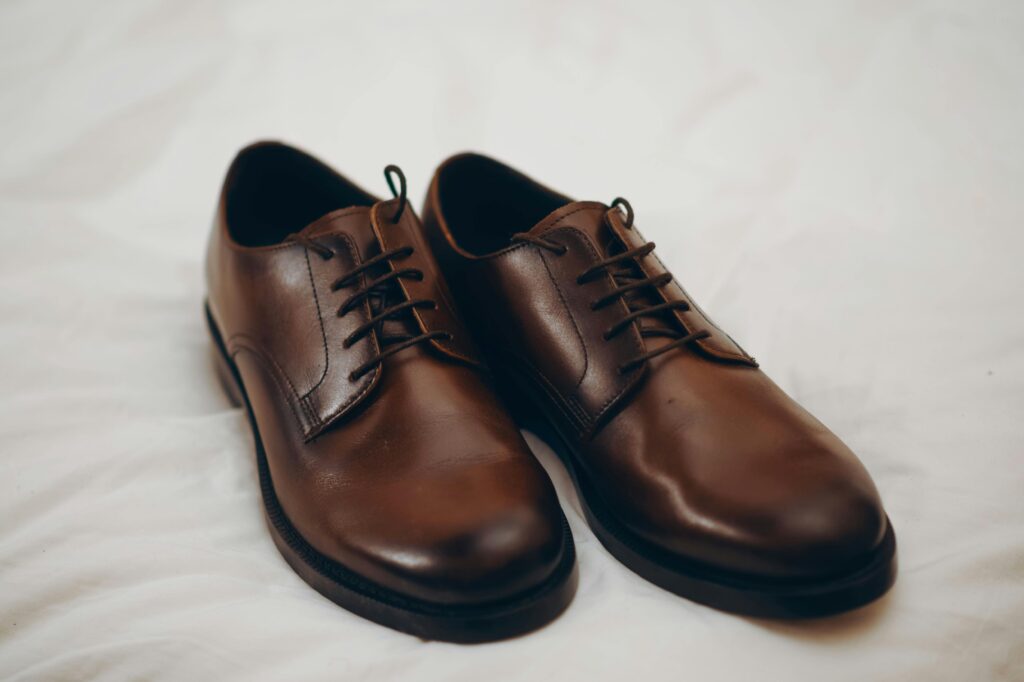 Pair of elegant brown leather formal shoes placed on a white fabric background.